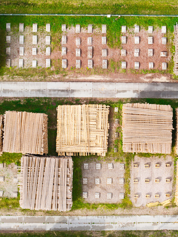 Aerial view of timber supply chain and sustainable forestry with stacked wooden logs and concrete blocks in a storage yard in Latvia. Aerial view of timber supply chain and sustainable forestry with stacked wooden logs and concrete blocks in a storage yard in Latvia.