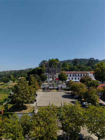 Aerial view of Pousada Mosteiro de Guimaraes a historic monastery with a stone facade surrounded by lush trees and a courtyard in Guimaraes Braga Portugal. Aerial view of Pousada Mosteiro de Guimaraes a historic monastery with a stone facade surrounded by lush trees and a courtyard in Guimaraes Braga Portugal.