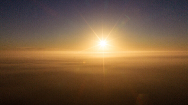 Aerial view of the sun rising over a thick layer of mist covering the landscape in Salisbury England United Kingdom. Aerial view of the sun rising over a thick layer of mist covering the landscape in Salisbury England United Kingdom.