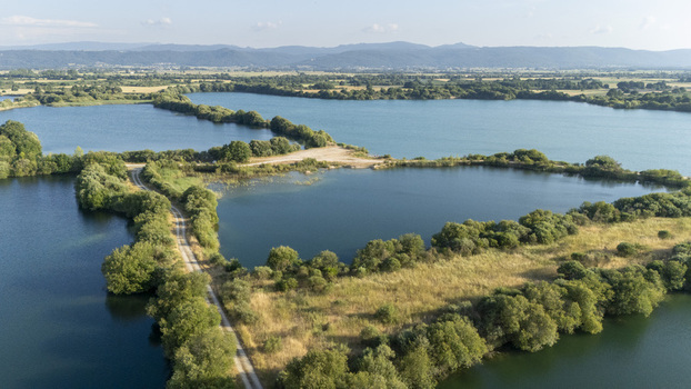 Aerial view of the Extraccion de aridos Lima SL site featuring water filled pits dirt access paths and surrounding green vegetation in Vilarino das Poldras Ourense Spain. Aerial view of the Extraccion de aridos Lima SL site featuring water filled pits dirt access paths and surrounding green vegetation in Vilarino das Poldras Ourense Spain.