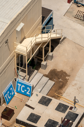 Aerial view of a modular construction building featuring an external metal staircase concrete steps and blue TC 2 signs on sandy ground in Dubai Dubai United Arab Emirates. Aerial view of a modular construction building featuring an external metal staircase concrete steps and blue TC 2 signs on sandy ground in Dubai Dubai United Arab Emirates.