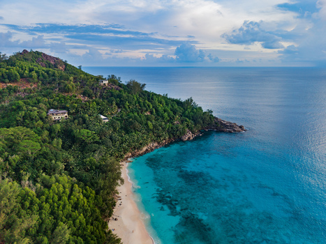 Aerial view of lush green hills cascading down to meet the turquoise sea embracing a serene beach with soft sand Quatre Bornes Mahe Island Seychelles. Aerial view of lush green hills cascading down to meet the turquoise sea embracing a serene beach with soft sand Quatre Bornes Mahe Island Seychelles.