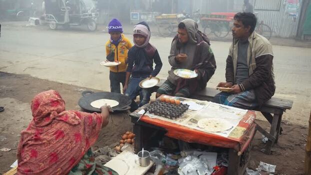 View of people eating street food at a stall in Bogura Bangladesh. View of people eating street food at a stall in Bogura Bangladesh.