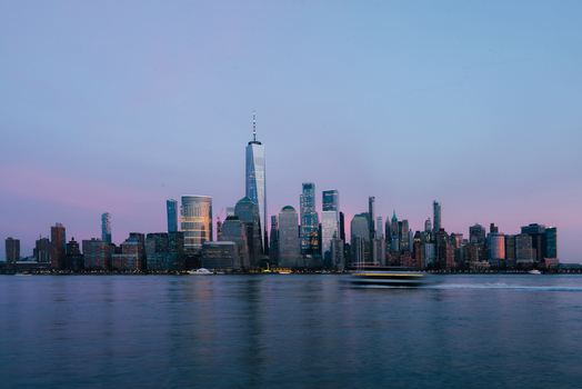 View of the One World Trade Center and the Manhattan skyline across the Hudson River at dusk with a soft pink and blue sky in New York New York United States.