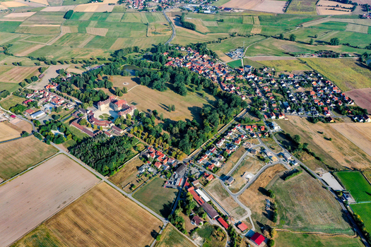 Aerial view of Schloss Weissenstein baroque palace with its extensive parkland and surrounding residential houses Pommersfelden Bavaria Germany.
