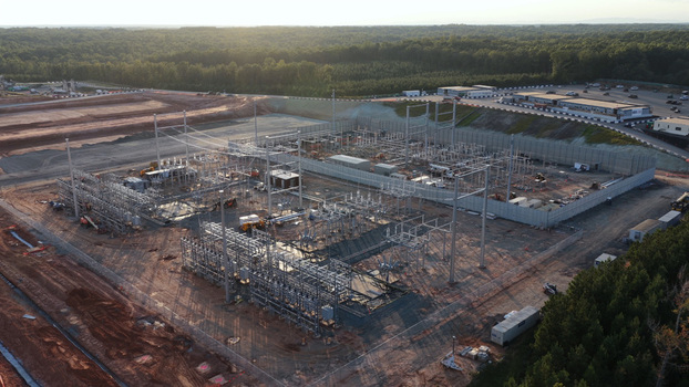 Aerial view of an electrical substation under construction featuring metal structures and power lines surrounded by a forest in Louisa County Virginia United States. Aerial view of an electrical substation under construction featuring metal structures and power lines surrounded by a forest in Louisa County Virginia United States.