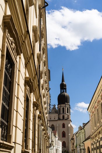 View of the historic St. Nicholas Basilica tower rising above narrow streets and ornate facades under a blue sky in Trnava Trnava Region Slovakia. View of the historic St. Nicholas Basilica tower rising above narrow streets and ornate facades under a blue sky in Trnava Trnava Region Slovakia.