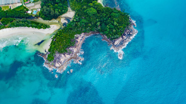 Aerial view of Grand Anse Mahe coastline featuring turquoise waters rocky cliffs and lush green vegetation in Grand Anse Mahe Seychelles. Aerial view of Grand Anse Mahe coastline featuring turquoise waters rocky cliffs and lush green vegetation in Grand Anse Mahe Seychelles.