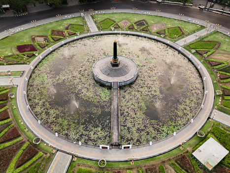 Aerial view of the Tugu Monument situated in the center of a circular lotus pond surrounded by manicured gardens and walkways in Malang East Java Indonesia.
