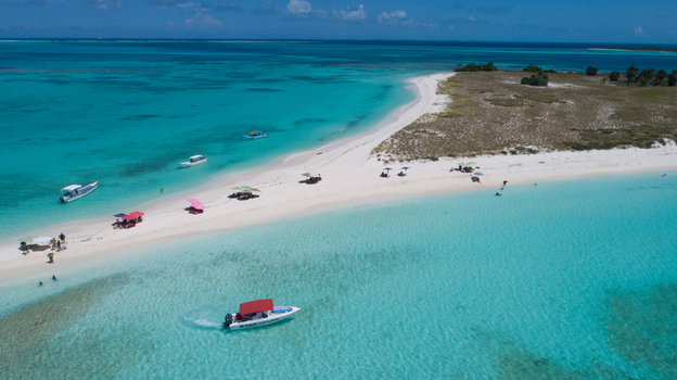 Aerial view of Los Roques archipelago featuring pristine white sand beaches turquoise water and small boats anchored near the shore in Los Roques Dependencias Federales Venezuela. Aerial view of Los Roques archipelago featuring pristine white sand beaches turquoise water and small boats anchored near the shore in Los Roques Dependencias Federales Venezuela.