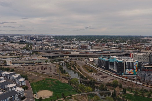 Aerial view of the Denver urban landscape featuring a complex highway interchange railway tracks the South Platte River and modern apartment buildings in Denver Colorado United States. Aerial view of the Denver urban landscape featuring a complex highway interchange railway tracks the South Platte River and modern apartment buildings in Denver Colorado United States.