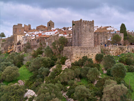 Aerial view of the ancient fortress standing guard over the whitewashed village nestled atop a verdant hill Castellar de la Frontera Andalucía Spain. Aerial view of the ancient fortress standing guard over the whitewashed village nestled atop a verdant hill Castellar de la Frontera Andalucía Spain.