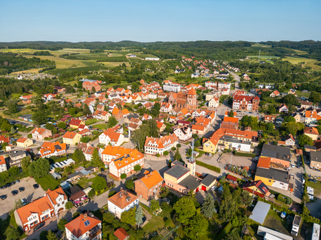 Aerial view of Tolkmicko with its historic red roofed buildings a central church and surrounding green fields under a clear blue sky in Tolkmicko Warmian Masurian Voivodeship Poland.
