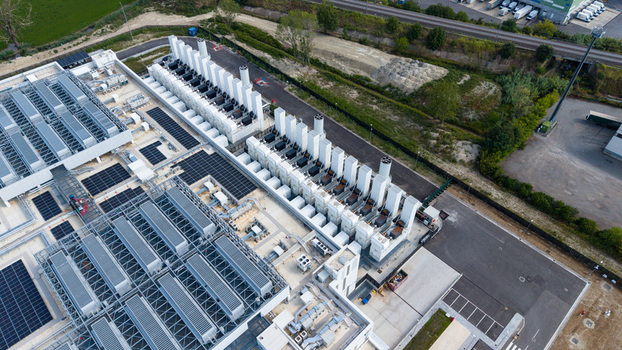 Aerial view of a modern hyperscale data center featuring rows of industrial cooling units and server infrastructure in Melegnano Lombardy Italy.