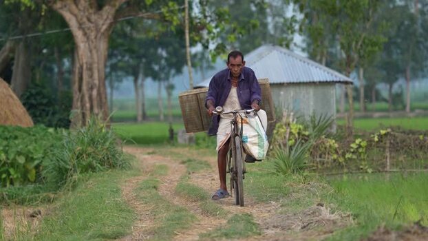 View of a man riding a bicycle with crates Bangladesh.
