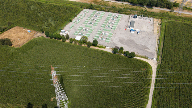 Aerial view of a Battery Energy Storage System with rows of green containers and an electrical substation surrounded by agricultural fields in Tavazzano con Villavesco Lombardy Italy.