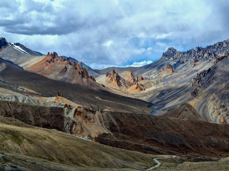 View of the rugged mountain landscape along the Penzi La road with dramatic rock formations and a winding dirt path Zanskar Ladakh India.