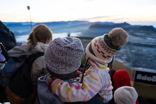 View of people wearing winter hats watching the sunrise over the misty mountain landscape from Adam s Peak Ratnapura Sabaragamuwa Province Sri Lanka. View of people wearing winter hats watching the sunrise over the misty mountain landscape from Adam s Peak Ratnapura Sabaragamuwa Province Sri Lanka.