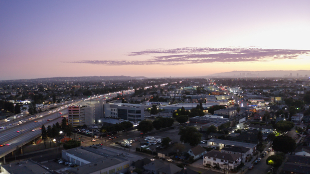 Aerial view of a busy freeway with flowing traffic at dusk surrounded by urban sprawl and residential buildings in Los Angeles California United States. Aerial view of a busy freeway with flowing traffic at dusk surrounded by urban sprawl and residential buildings in Los Angeles California United States.