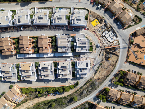 Aerial view of modern residential villas and a construction site with flat roofs solar panels and paved streets in Moraira Valencian Community Spain.