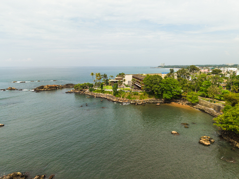 Aerial view of a coastal resort building on a rocky peninsula surrounded by lush green trees and the calm Indian Ocean in Galle Southern Province Sri Lanka. Aerial view of a coastal resort building on a rocky peninsula surrounded by lush green trees and the calm Indian Ocean in Galle Southern Province Sri Lanka.