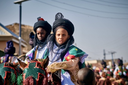 Zaria city Nigeria 21 March 2026 View of two solemn young riders in richly embroidered jewel toned robes and dark turbans parading on festively adorned horses. Zaria city Nigeria 21 March 2026 View of two solemn young riders in richly embroidered jewel toned robes and dark turbans parading on festively adorned horses.