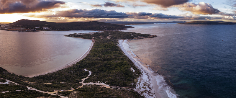 Aerial view of Quaranup Beach with lush coastal vegetation sandy shores and calm waters under a dramatic sunset sky in Vancouver Peninsula Western Australia Australia.