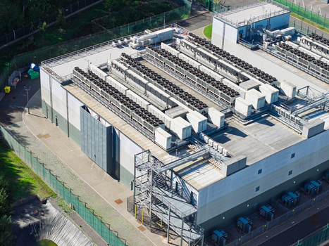 Aerial view of a data center facility with rows of industrial cooling units on the roof metal staircases and security fencing in the United Kingdom.