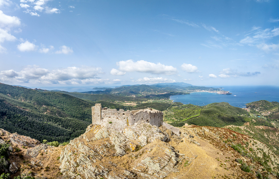 Aerial view of Castello del Volterraio perched on a rocky hilltop overlooking the Mediterranean Sea with lush green hills in Portoferraio Toscana Italy.