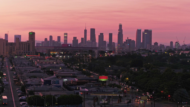 Aerial view of the Los Angeles skyline during a vibrant pink sunset featuring modern skyscrapers urban streets and residential buildings in Los Angeles California United States.
