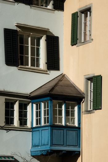 Zurich Switzerland 02 April 2023 View of the architectural contrast between the blue bay window and open shutters against the pastel walls capturing the essence of old world charm. Zurich Switzerland 02 April 2023 View of the architectural contrast between the blue bay window and open shutters against the pastel walls capturing the essence of old world charm.