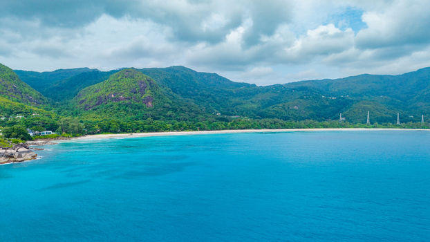 Aerial view of the white sand beach turquoise ocean waters and lush green mountains of Grand Anse Village Grand Anse Mahe Seychelles. Aerial view of the white sand beach turquoise ocean waters and lush green mountains of Grand Anse Village Grand Anse Mahe Seychelles.