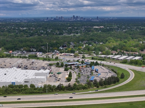 Aerial view of a large retail store and parking lots surrounded by lush green trees with the city skyline in the distance under a cloudy sky Columbus Ohio United States. Aerial view of a large retail store and parking lots surrounded by lush green trees with the city skyline in the distance under a cloudy sky Columbus Ohio United States.