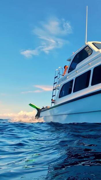 View of a person swimming near a boat in Bali Indonesia. View of a person swimming near a boat in Bali Indonesia.
