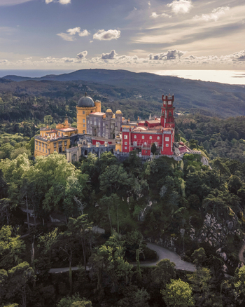Aerial view of Pena Palace a hilltop Romanticist palace in parkland at sunset Sintra Lisbon Portugal.