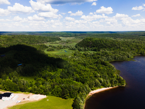 Aerial view of Commanda Lake surrounded by dense forests rolling hills and a building near the shoreline under a bright sky in Restoule Ontario Canada. Aerial view of Commanda Lake surrounded by dense forests rolling hills and a building near the shoreline under a bright sky in Restoule Ontario Canada.