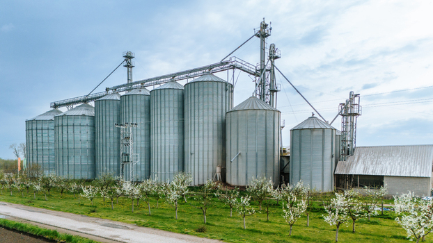 Aerial view of silver silos gleaming under a vast sky contrasted by the delicate blossoms of trees Sremska Mitrovica Vojvodina Serbia. Aerial view of silver silos gleaming under a vast sky contrasted by the delicate blossoms of trees Sremska Mitrovica Vojvodina Serbia.