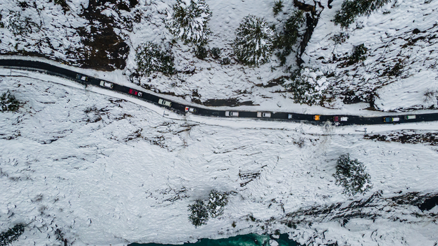 Aerial view of a winding road snaking through a snow laden valley where a line of cars navigates the wintry landscape Sharda Azad Kashmir Pakistan. Aerial view of a winding road snaking through a snow laden valley where a line of cars navigates the wintry landscape Sharda Azad Kashmir Pakistan.