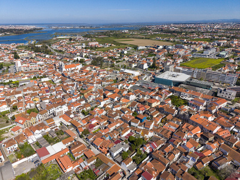 Aerial view of a vibrant tapestry of orange tiled rooftops sprawling towards the serene blue estuary under a clear sky Ilhavo Aveiro Portugal. Aerial view of a vibrant tapestry of orange tiled rooftops sprawling towards the serene blue estuary under a clear sky Ilhavo Aveiro Portugal.