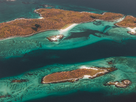 Aerial view of the islands of Senja featuring turquoise waters sandy beaches and rocky terrain in Senja Troms Norway.