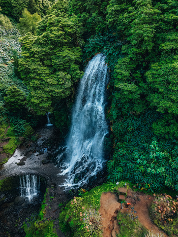 Aerial view of cascading waterfall amidst verdant foliage a symphony of blues and greens a tranquil escape in nature s embrace Achada Açores Portugal. Aerial view of cascading waterfall amidst verdant foliage a symphony of blues and greens a tranquil escape in nature s embrace Achada Açores Portugal.