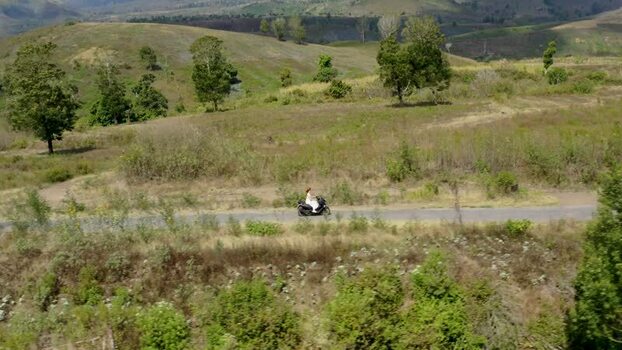 Aerial view of a person riding a scooter on a rural road Indonesia. Aerial view of a person riding a scooter on a rural road Indonesia.
