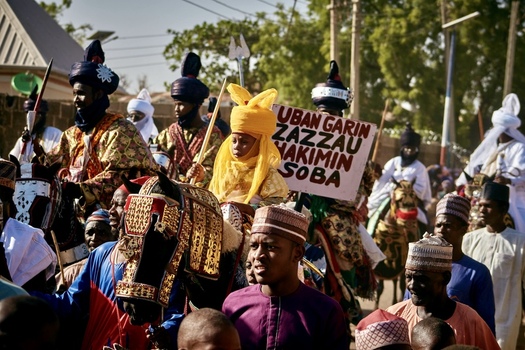 Zaria City Nigeria 21 March 2026 View of a vibrant procession of people on horseback adorned in rich contrasting traditional garments under a bright sky. Zaria City Nigeria 21 March 2026 View of a vibrant procession of people on horseback adorned in rich contrasting traditional garments under a bright sky.