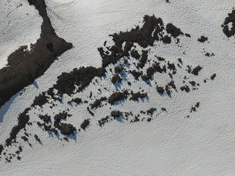 Aerial view of the south slope of Mount Etna with dark volcanic rock formations contrasting against a blanket of white snow in Nicolosi Sicilia Italy. Aerial view of the south slope of Mount Etna with dark volcanic rock formations contrasting against a blanket of white snow in Nicolosi Sicilia Italy.