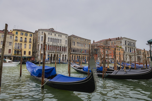 Venice Italy 06 May 2022 View of gondolas moored on the Grand Canal with historic Venetian buildings in the background under a cloudy sky.