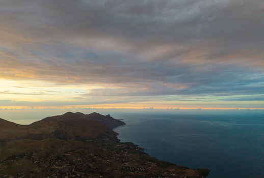 Aerial view of the rugged coastline of Sicily at sunset featuring rolling hills calm sea and a dramatic cloudy sky over the Mediterranean landscape Palermo Sicily Italy. Aerial view of the rugged coastline of Sicily at sunset featuring rolling hills calm sea and a dramatic cloudy sky over the Mediterranean landscape Palermo Sicily Italy.