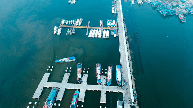 Aerial view of Port of Kali Adem featuring numerous wooden boats docked at concrete piers along the calm harbor waters in Kecamatan Penjaringan Daerah Khusus Ibukota Indonesia. Aerial view of Port of Kali Adem featuring numerous wooden boats docked at concrete piers along the calm harbor waters in Kecamatan Penjaringan Daerah Khusus Ibukota Indonesia.