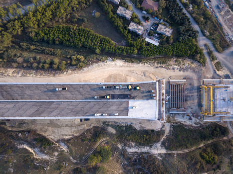 Aerial view of a bridge construction site with heavy machinery and steel girders on the unfinished deck surrounded by green hills in Istanbul Istanbul Turkiye.