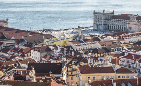 Aerial view of the historic Praca do Comercio with its iconic yellow buildings red tiled rooftops and the Tagus river in the background in Lisbon Lisbon Portugal.