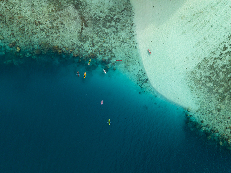 Aerial view of turquoise waters meet the sandy shore kayaks dotting the deep blue a tranquil contrast of colors and textures at Menjangan Kecil Island Karimunjawa Indonesia.